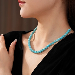 Detailed view of turquoise beaded necklace with natural texture on a model neck