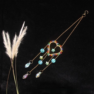 Macro shot of heart-shaped crystal suncatcher with aurora teardrop pendants on black fabric