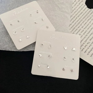 Set di orecchini in argento con forme geometriche varie su cartoncino settimanale
