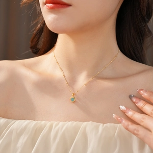 Detailed close-up of gold plated necklace with a round cat-eye stone cube pendant