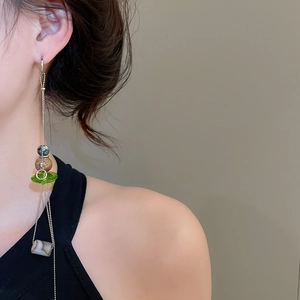 Detail of ethnic tassel earring with green marble beads and long silver metal chains