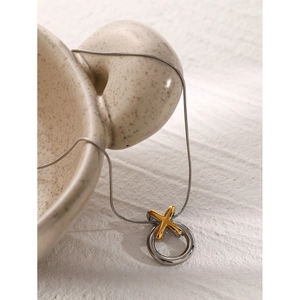Detailed macro view of two-tone gold and silver XO pendant on a sleek snake chain