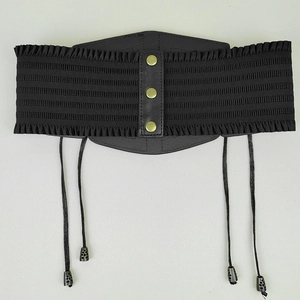 Détail d'une ceinture corset noire vintage avec boutons en laiton et texture plissée