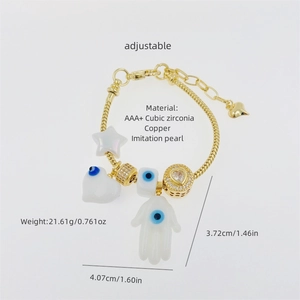 Detail of gold chain bracelet with Hamsa Hand, evil eye heart and zircon charms