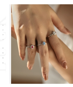 Close-up of three 925 silver rings with oval red, blue, and clear sparkling gemstones