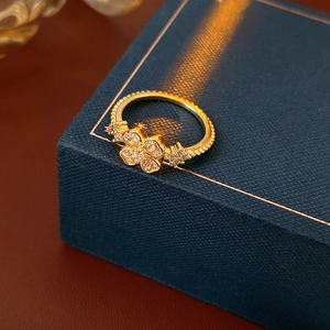 Macro shot of gold-plated clover ring with shimmering zircons on a dark jewelry box