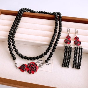 Detail of red gourd pendants and black beaded tassels jewelry set in a display tray