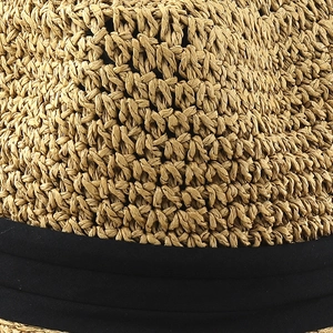 Close-up of natural straw texture and black cotton ribbon on a sun hat