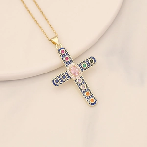 Gold cross pendant necklace with blue enamel and colorful zircon on white ceramic tray