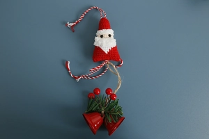 Detail of hand-knitted Santa bag charm with metal bells and festive red berries