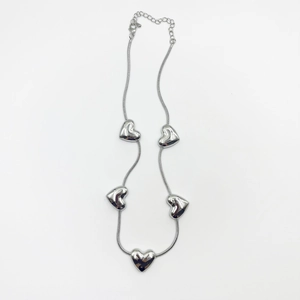 Close-up of five silver heart-shaped pendants on a snake chain with lobster clasp