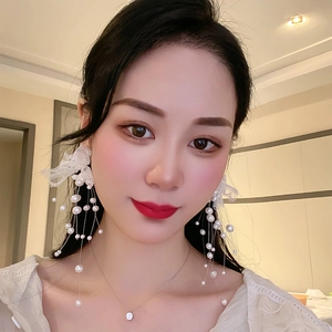 Boucles d'oreilles fleurs en dentelle avec longs glands de perles portées par un modèle