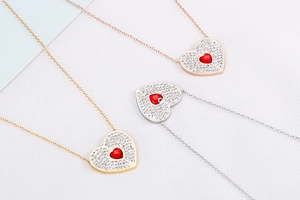 Detailed view of heart pendants with pavé crystals and red stones in gold, silver and rose gold