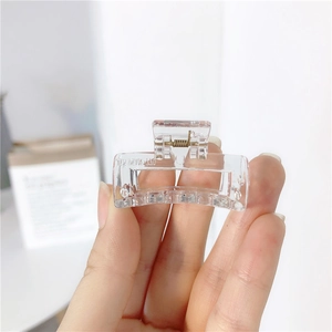 Macro detail of a transparent square claw clip with a durable gold metal spring