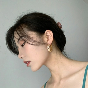 Close-up of gold chain-link hoop earrings with sparkling crystals worn by a model