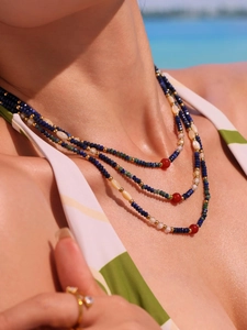 Close-up of lapis lazuli and agate beaded necklace on model with beach background