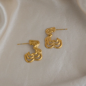 Macro shot of 18K gold plated multi-layer hollow wave earrings on satin fabric