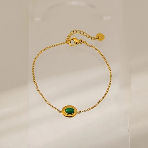 Detail view of gold-plated stainless steel bracelet with green oval gemstone pendant