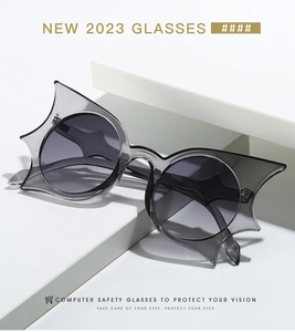 Detail of bat-wing geometric sunglasses in grey resin on a white minimalist pedestal