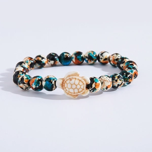 Detailed view of colorful turquoise beads with a white sea turtle charm on a beaded bracelet