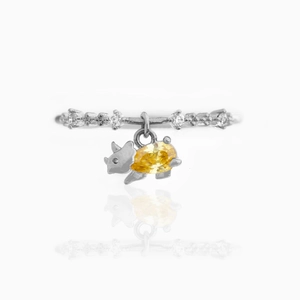 Detail of 18K gold dinosaur ring featuring a pig pendant with a pear-cut yellow zircon stone