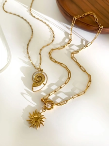 Detailed shot of gold necklaces with shell and sunburst pendants and toggle clasp