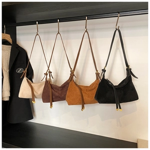 Macro shot of four suede crescent handbags in beige, brown, tan, and black with fringe detail
