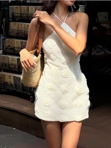 Robe dos nu blanche à licou avec fleurs 3D dans un décor de rue vintage élégant
