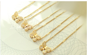 Macro shot of gold butterfly necklaces with zircon pavé on 18k gold plated titanium