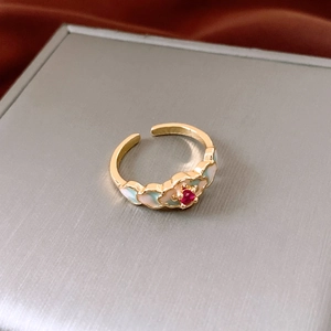 Detailed macro view of 18K gold plated ring with red zircon and colorful floral enamel