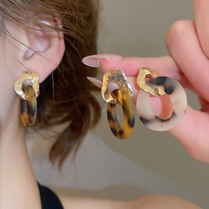 Close-up of geometric acrylic earrings with leopard pattern and gold-tone metal studs