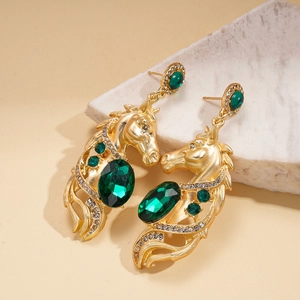 Detailed macro view of vintage gold horse head earrings with oval green gemstones and crystals