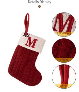 Detail of red cable knit Christmas stocking featuring embroidered letter M with mini hat