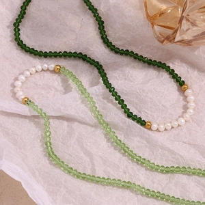 Detail of handmade green faceted crystal beads and freshwater pearls on steel necklace