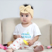 Close-up of a baby wearing a soft elastic knit headband with a large pale yellow bow