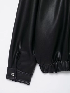 Detail view of black faux leather jacket with elastic hem and metal snap buttons on cuffs