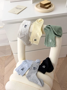 Detail of six colorful crew socks with heart embroidery on a beige chair