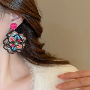Close-up of ethnic embroidered flower earring with colorful beads on a model
