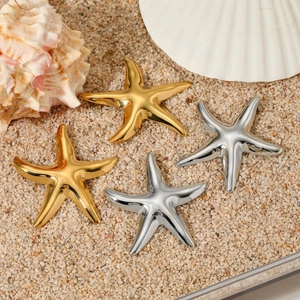 Gold and silver starfish earrings on a sandy beach with shells for an ocean-themed style