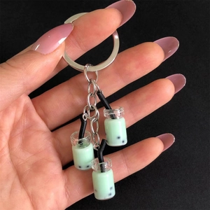 Detail of three mint green bubble tea resin pendants on a metal keychain held by hand