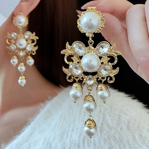 Close-up of golden vintage pearl tassel earrings with intricate flower design