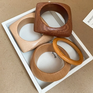 Détails de quatre bracelets en bois naturel aux textures variées dans un plateau