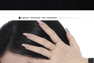 Macro shot of gold and silver minimalist wave rings worn together for a layered style