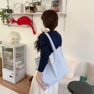 Detailed view of striped canvas tote bag texture with minimalist white woven label