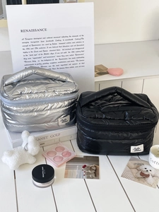 Detailed close-up of quilted nylon cosmetic bags in silver and black with dual zippers