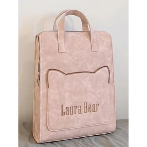 Detailed view of the pink backpack featuring a cat-ear shaped front pocket and embroidery