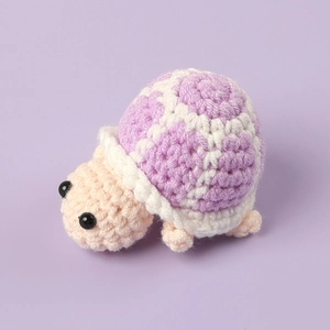 Close-up of pink and purple crochet turtle doll showing detailed handmade yarn texture