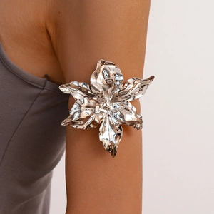 Macro detail of a silver liquid metal ruffled flower arm cuff on a female model
