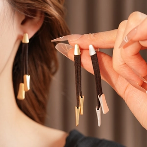 Detail of vintage leather tassel earrings in gold and silver finish on model