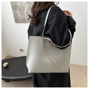 Light gray large-capacity leather tote bag worn by model in a minimalist home setting